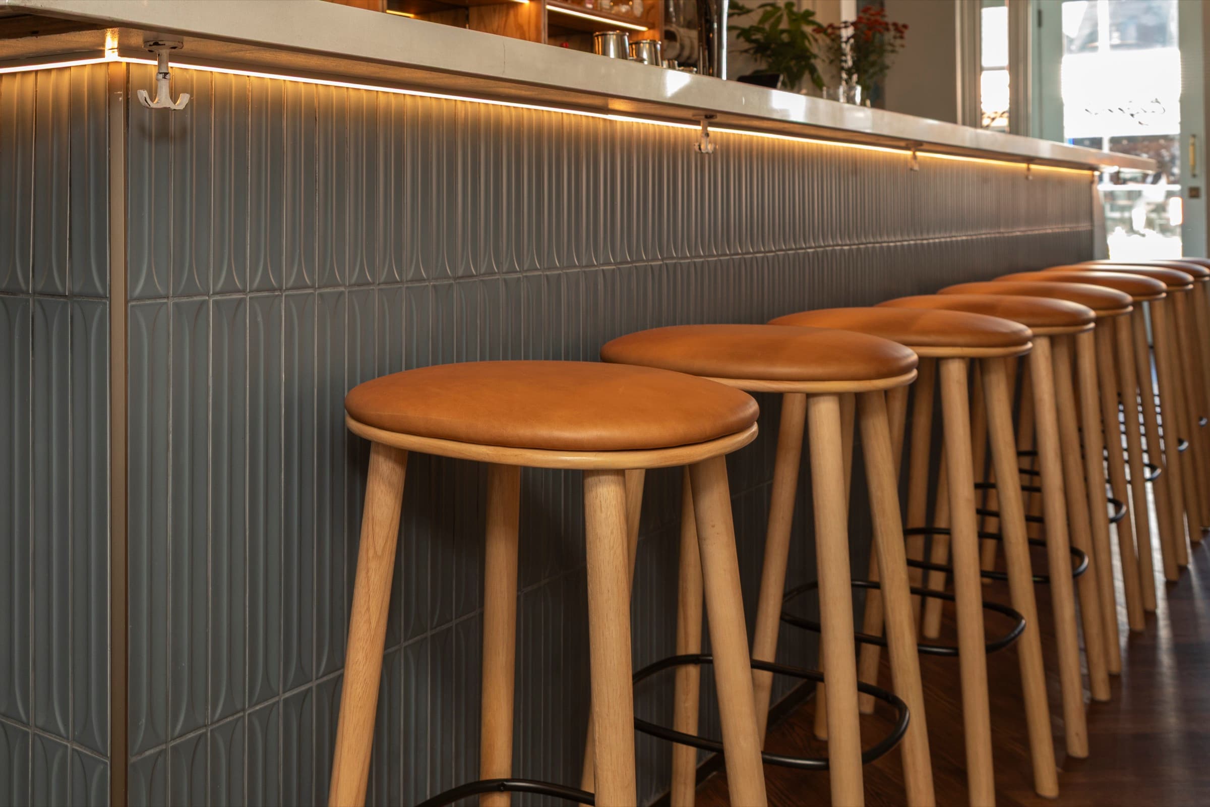 Bar Eugenie — blue tile bar front with leather stools and LED strip lighting
