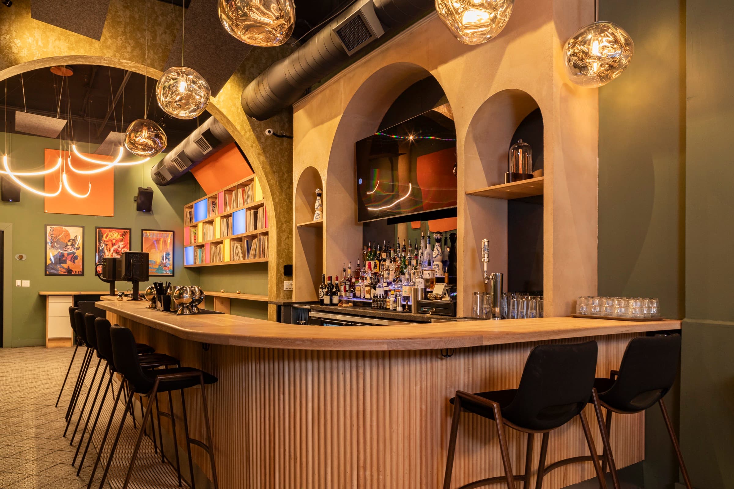 Boogie bar interior through custom decorative arch — slatted wood bar, pendant lights, and patterned floor tile